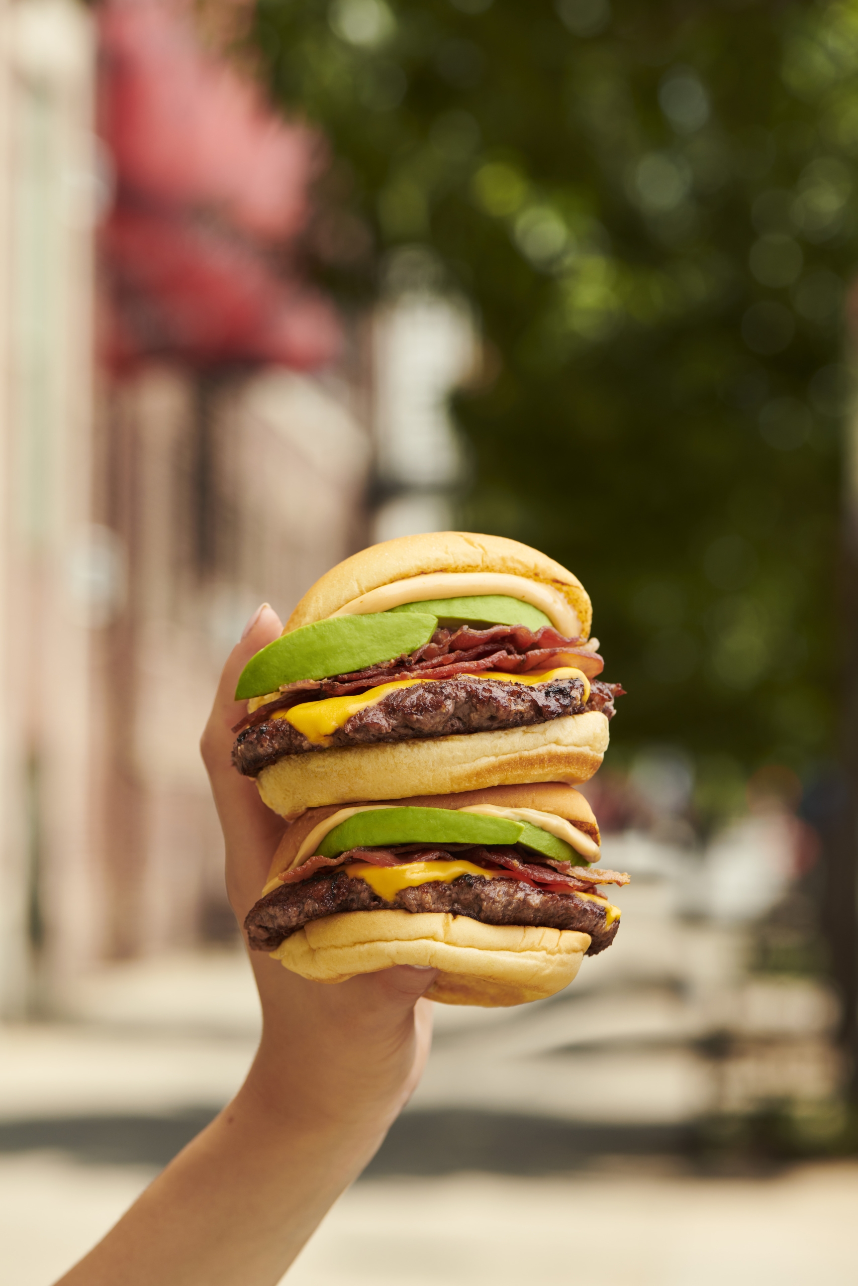 hand holding a double burger with cheese